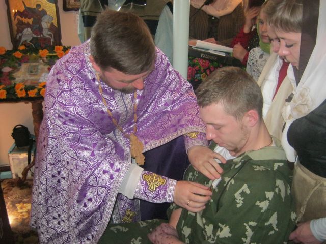 Священик Михайло Шевчук вручає нагороду Герою