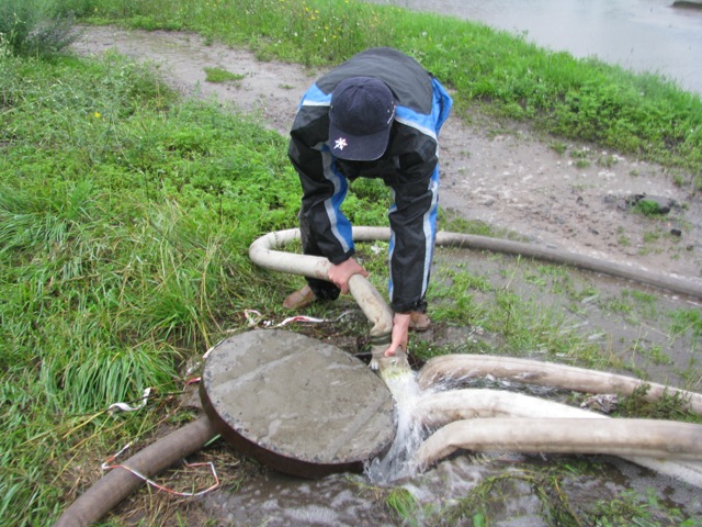 Андрій Бортник намагається підняти кришку, аби показати подальший «шлях» води